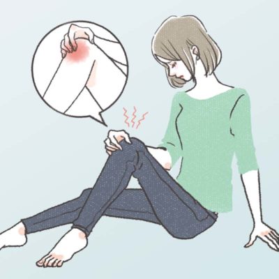 生理前のひざの関節痛に悩み、膝をさする女性